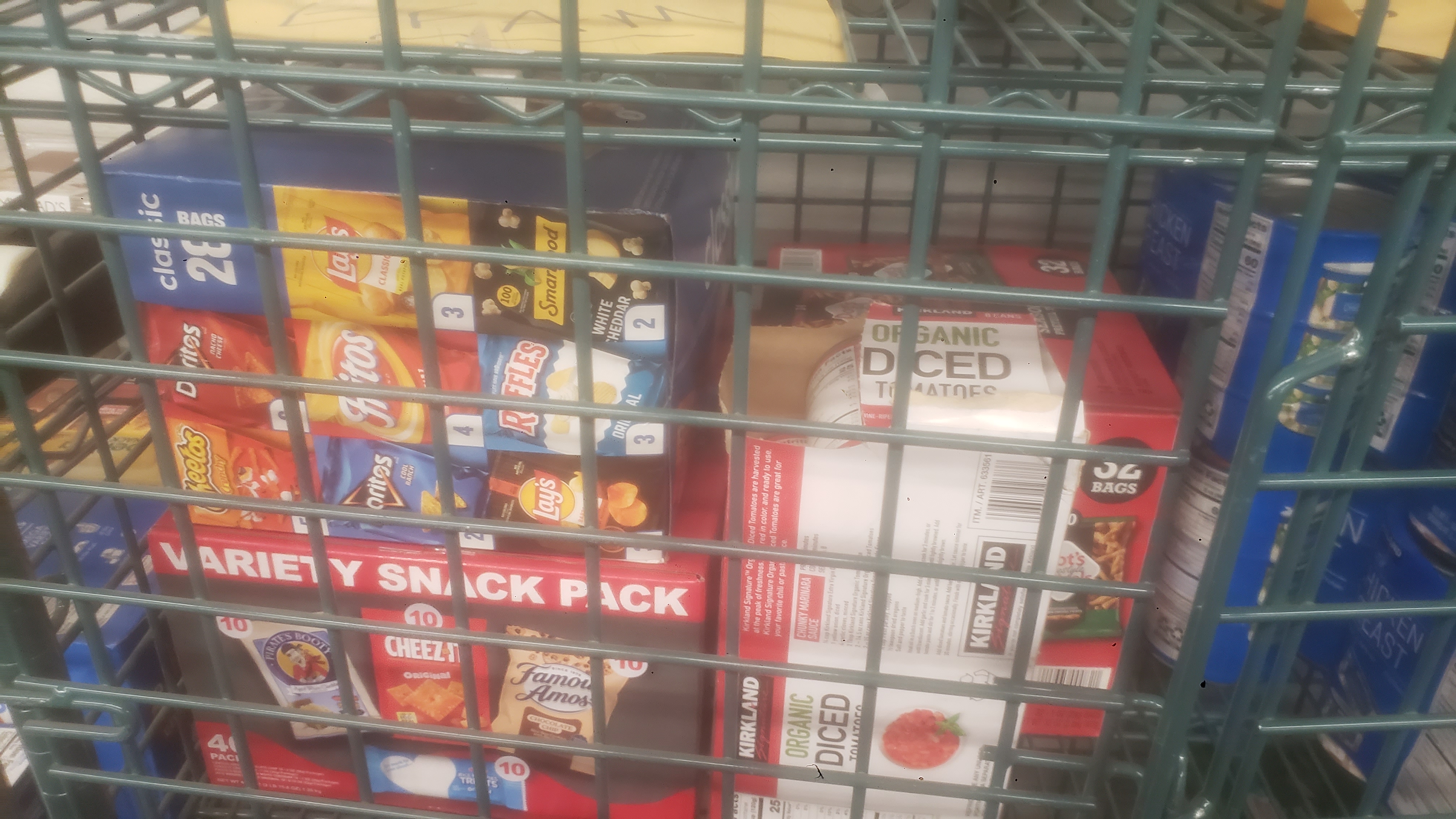 Boxes of chips and diced tomatoes in a cage shelf.